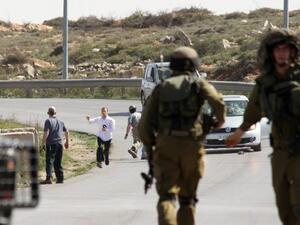 Israeli soldiers are seen close to settlers who appear to attack a photographer's car. (AFP/File)