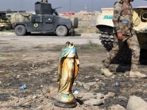 An Iraqi soldier walks past a broken statue of the virgin Mary. (AFP/File)