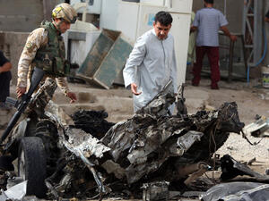 Iraqi soldiers inspect the wreckage of a car following an explosion. (AFP/File)