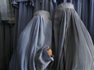 Two Afghan women clad in burqas whisper in a shop in Kabul, 2007. (AFP/File)