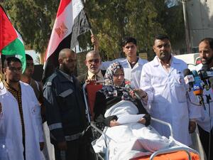 Palestinian medical staff stand next to a patient as she speaks to the media, calling on Egypt to open the Rafah crossing in the southern Gaza Strip on November 6, 2014. (AFP/Said Khatib)