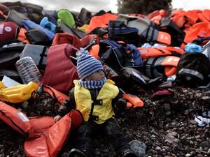 A child sits among life jackets on the Greek island of Lesbos after crossing the Aegean sea from Turkey with other refugees, October 25th 2015. (AFP/File)