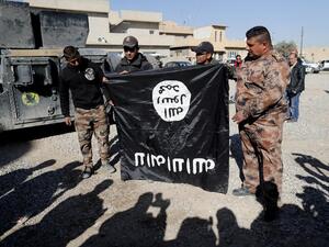 Iraqi army soldiers hold a flag from the Daesh jihadist group up-side-down. (AFP/File)