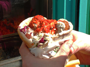 A patron of The Falafel Ace holding the restaurant’s acclaimed falafel sandwich, which is covered in hot sauce. (WikiMedia/Creative Commons)