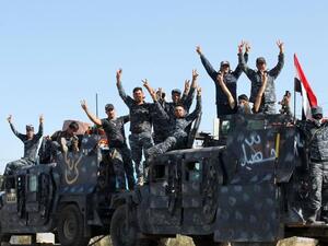 Iraqi forces gesture as they gather at the Qayyarah military base in preparation of an assault. (AFP/File)