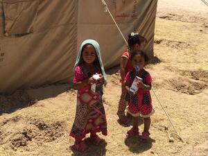 Displaced Iraqi children stand outside a tent at a newly-opened camp. (AFP/File)