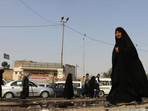 An Iraqi woman walks past a pool of blood on the aftermath of a suicide bomb. (AFP/File)
