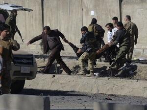 Afghan security personnels carry a victim at the site of a suicide car bomb next to a police base in Kabul on Feb 1, 2016. (AFP/Shah Marai)