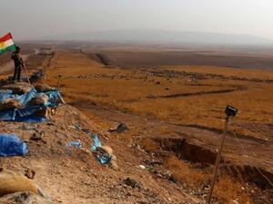 An Iraqi Kurdish Peshmerga fighter, next to a Kurdish flag. (AFP/File)