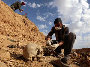 An Iraqi man inspects the remains of members of the Yazidi minority killed by the Daesh jihadist group, February 3, 2015. (AFP/Safin Hamed)