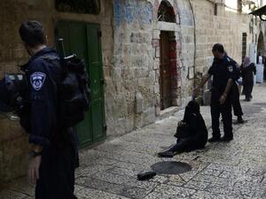 A Palestinian woman is blocked from entering the al-Aqsa Mosque compound, sits on the ground during a tension moment between Israeli security forces. (AFP/File)