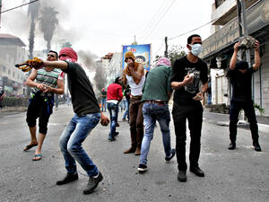 Palestinian youth throw rocks at Israeli troops in protest. (AFP/Hazem Bader)