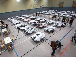 Migrants walk next to camp beds in a makeshift refugee shelter in a gym in Stern, Germany. (AFP/File)