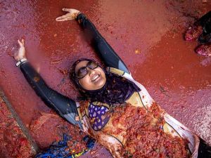 A reveller lies in tomato pulp during the annual "tomatina" festivities in Spanish village. (AFP/File)