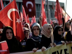 A group of women holds a banner as Pro-Erdogan protesters wave Turkish flags. (AFP/File)