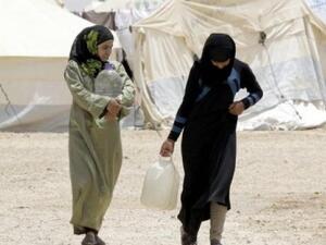 Syrian refugees carry water containers as they walk through the northern Jordanian Zaatari refugee camp on May 18, 2013. (AFP/Khalil Mazraawi)