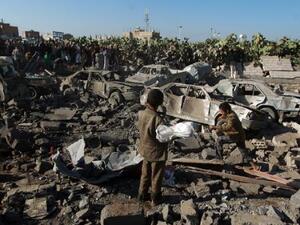 Yemenis stand at the site of a Saudi air strike against Houthi rebels near Sanaa Airport. (AFP/File)  