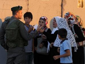 QALANDIA : Palestinian Muslim worshipers talk with an Israeli border guard as they walk towards the Qalandia checkpoint between Ramallah and Jerusalem, in the occupied West Bank. AFP PHOTO/ABBAS MOMANI
