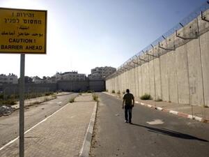فلسطيني يمشي بجانب جدار العزل في بيت حنينا شرق القدس/أ.ف.ب