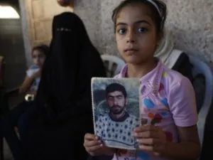 طفلة فلسطينية تحمل صورها لوالدها المعتقل في سجون الإحتلال الإسرائيلية