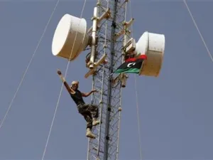 مقاتل من المناوئين للقذافي يشير بعلامة النصر بعد ان رفع علم المجلس الوطني الانتقالي على برج للاتصالات في بلدة تبعد 15 كيلومترا شمالي بني وليد 