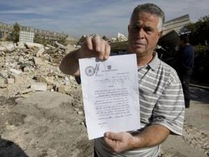 الفلسطيني عزيز زبلح يعرض حكما بوقف قرار تدمير منزله امام ركام المنزل في حي الطور