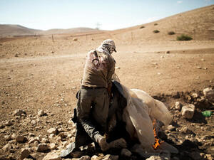 A Palestinian man burns the remains of his previous encampment, in the Jordan Valley settlement of Makhoul September 25, 2013.  The land was closed to Palestinians after Israel declared it a "closed military zone." (Image credit: AFP)
