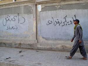 A Pakistani man walks past graffiti reading "Abu Bakr al-Baghdadi," the name of the leader of Daesh, in Quetta, Pakistan. (AFP/Banaras Khan)