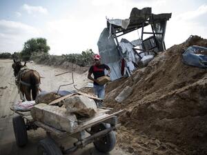 A Palestinian man loads stones on a cart next to a crater on August 22, 2016 in Beit Lahia in the northern Gaza Strip, following an Israeli airstrike the day before. (AFP/Mahmud Hams)