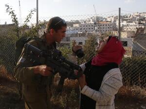 An Israeli soldier scuffles with a Palestinian woman who is trying to film the scene of a reported Palestinian stabbing attack on a soldier near the Jewish settler enclave of Tal Rumeda in the city centre of the West Bank town of Hebron on September 16, 2016. (AFP/Hazem Bader)