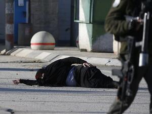 A Palestinian woman lies on the ground after she was shot and wounded by Israeli security forces while approaching the Qalandia checkpoint with a knife, between Jerusalem and the occupied West Bank on December 30, 2016, according to Israeli police. (AFP/Abbas Momani)