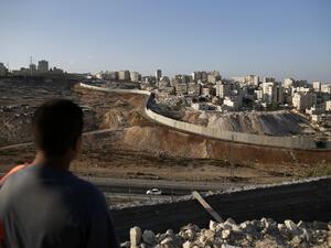A picture taken on October 18, 2016 from the east Jerusalem Arab neighbourhood of Issawiya shows a Palestinian youth looking on as the Palestinian Shuafat refugee camp (R) is seen behind the controversial Israeli separation wall. (AFP/Ahmad Gharabli)