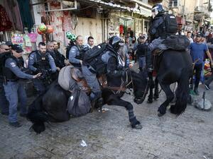 An Israeli border policeman and his horse fall in Jerusalem's Old City on April 29, 2017 during clashes with Palestinian demonstrators following a gathering in support of Palestinians imprisoned in Israeli jails. (AFP/Ahmad Gharabli)