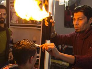 This barber in Gaza cuts hair using an open flame. (Screen grab)