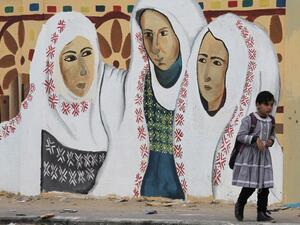 A Palestinian girl walks past a mural on a street in Rafah, in the southern Gaza Strip, on March 30, 2017, which marks Land Day. Land Day marks the killing of six Arab Israelis during 1976 demonstrations against Israeli confiscations of Arab land. (AFP/Said Khatib)