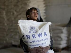 A Palestinian child in Gaza holds a bag of flour distributed by UNRWA. (AFP/File)