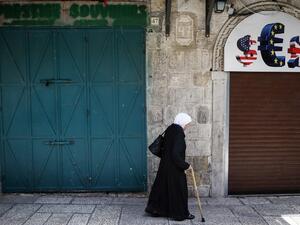 An elderly woman walks past closed shops in the Old City of Jerusalem on April 27, 2017, during a trade strike in support of Palestinian prisoners on hunger strike in Israeli jails. (AFP/Ahmad Gharabli)