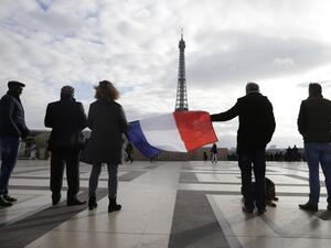 Mourners hold a French flag in Paris. (AFP/Kenzo Tribouillard)