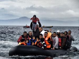 A man holds up a young boy as a boat carrying migrants and refugees arrives at the Greek island of Lesbos after crossing the Aegean sea from Turkey. (AFP Photo/Aris Messinis)