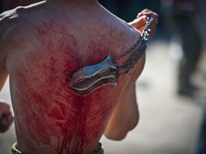 An Afghan Shiite Muslim man beats himself with chains and blades during a Muslim ritual on the last day of Ashura celebrations in the streets of Kabul on December 16, 2010. 