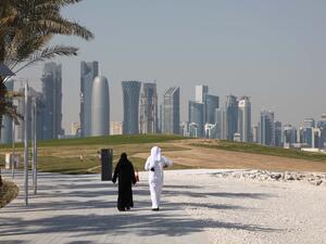 Arabic couple walking in front of the Doha downtown skyline. (Shutterstock/Philip Lange)