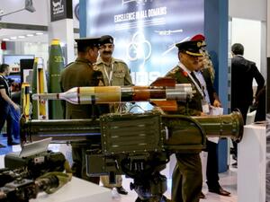 Uniformed visitors walk past a rocket-propelled grenade launcher on display /AFP