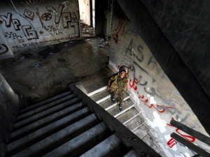 A female fighter from the Kurdish People's Protection Units (YPG) descends stairs in an abandoned building in Raqa's eastern al-Sanaa neighbourhood, on the edge of the old city, on August 13, 2017 / AFP
