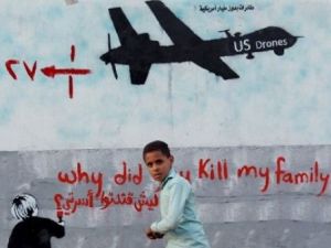 Yemeni boy walk past a mural depicting a U.S. drone, which reads, "Why did you kill my family," in the capital Sanaa. (AFP/ File)