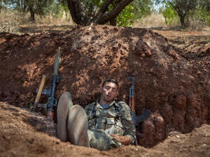 A rebel fighter takes a nap after his night shift in a trench along the highway that connects Idlib city with Latakia, 100m away from the Syrian regime's forces's positions, on July 15, 2013. (Source: AFP/DANIEL LEAL OLIVAS)