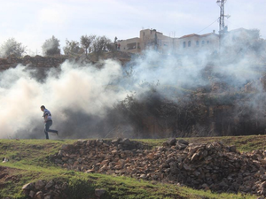 A Palestinian man runs away from tear gas canisters fired by Israeli soldiers during a protest outside Ofer Prison near Ramallah. (image: Hunter Stuart/Al Bawaba) 