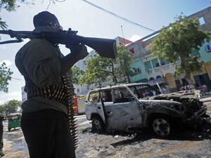 A Somali soldier patrols next to the remains of a car targeted in a bomb attack in Mogadishu on September 5, 2016. (AFP/Mohamed Abdiwahab)