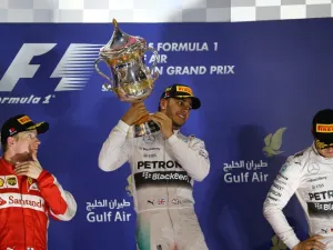 Mercedes AMG Petronas British driver Lewis Hamilton (C) hold his winners trophy as he stands on the podium after winning the Formula One Bahrain Grand Prix, ahead of Scuderia Ferrari Finnish driver Kimi Raikkonen (L) in second place and Mercedes AMG Petronas German driver Nico Rosberg (R) in third at the Sakhir circuit in the desert south of the Bahraini capital, Manama, on April 19, 2015. AFP PHOTO / MARWAN NAAMANI
MARWAN NAAMANI / AFP
