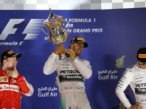 Mercedes AMG Petronas British driver Lewis Hamilton (C) hold his winners trophy as he stands on the podium after winning the Formula One Bahrain Grand Prix, ahead of Scuderia Ferrari Finnish driver Kimi Raikkonen (L) in second place and Mercedes AMG Petronas German driver Nico Rosberg (R) in third at the Sakhir circuit in the desert south of the Bahraini capital, Manama, on April 19, 2015. AFP PHOTO / MARWAN NAAMANI
MARWAN NAAMANI / AFP