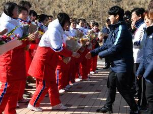 Members of North Korean women's ice hockey team (in white and red) are welcomed by members of the South Korean team (in blue) as they arrive at South Korea's national training centre in Jincheon on January 25, 2018. 
Song Kyung-Seok / POOL / AFP